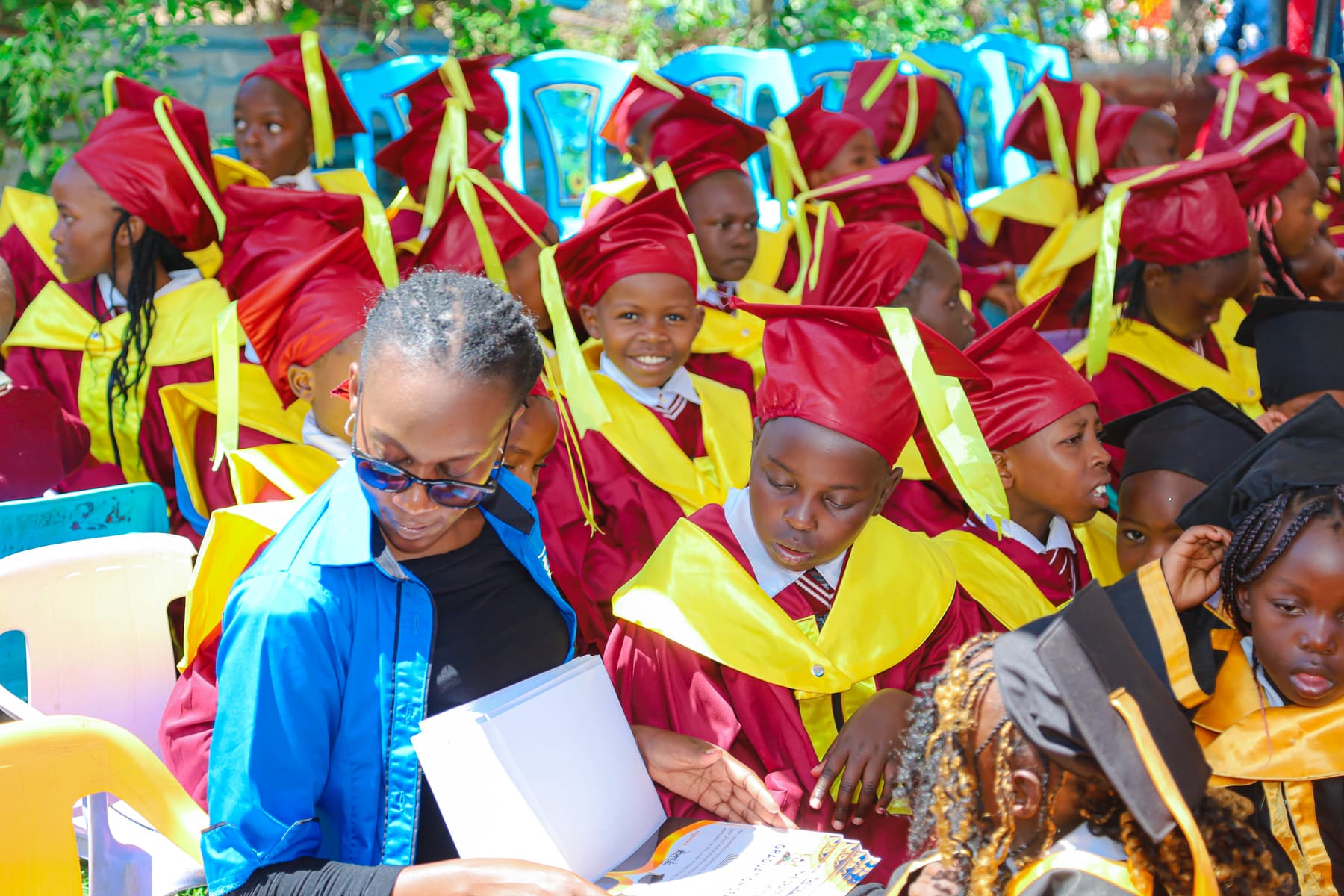 Graduating learners in crimson and gold gowns seated at the 2025 ceremony