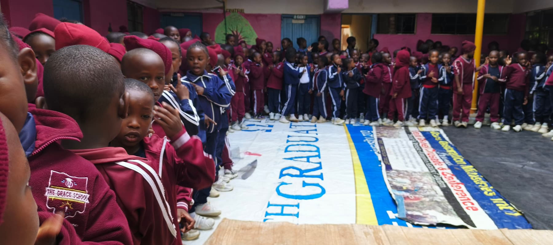 Grace Schools learners lined up at a school assembly beside painted banners